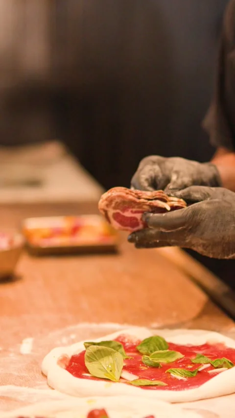 Professional Chef Adding Prosciutto to Fresh Pizza in Commercial Kitchen 動画素材 338321537