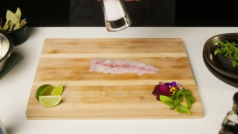 Professional Chef adding salt on raw white fish fillet on cutting board close-up Stock Footage 160901954
