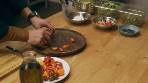 Professional chef arranging sliced tomatoes onto a wooden plate in industrial ki Stock Footage 199455971