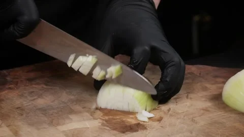 Professional Chef in Black Gloves Slicing a White Onion on a Wooden Cutting Boar Stock Footage 331636084
