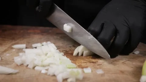 Professional Chef in Black Gloves Slicing a White Onion on a Wooden Cutting Boar Stock Footage 331636163