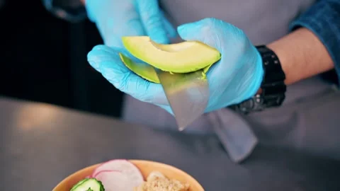 Professional chef in blue gloves peeling fresh avocado with sharp knife for.. Stock Footage 339379695
