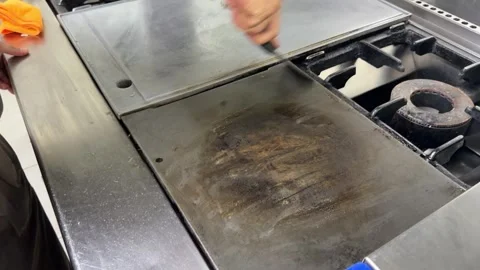 Professional chef cleaning a dirty griddle with a scraper Vídeos de archivo 344100051