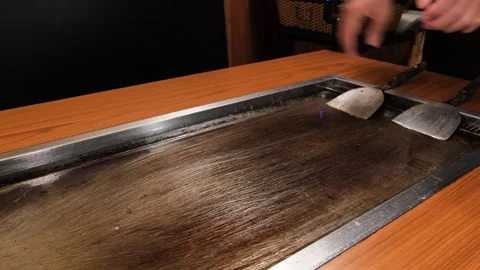 Professional Chef Cleaning Hot Teppanyaki Iron Griddle with Spatulas Stock Footage 333520360