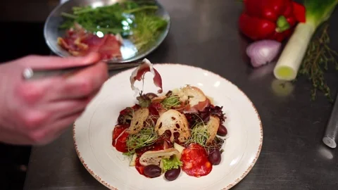 Professional chef cook arranging salad ingredients on white plate to make Stock Footage 106977414