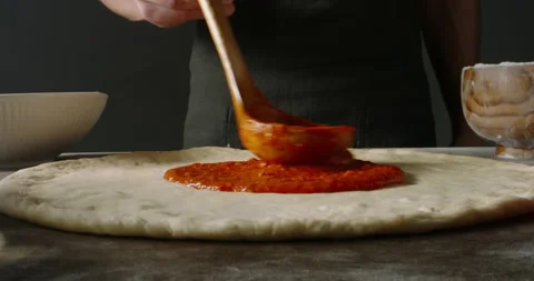 Professional chef is cooking pizza, applying delicious tomato sauce on dough Stock Footage 156142070