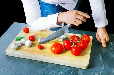 Professional chef cuts vegetables with a sharp knife from Damascus steel. Stock Photos