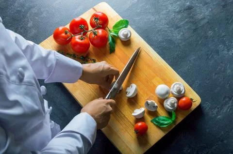 Professional chef cuts vegetables with a sharp knife from Damascus steel. Stock Photos
