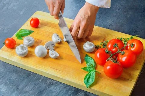 Professional chef cuts vegetables with a sharp knife from Damascus steel. Stock Photos