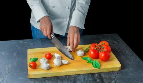 Professional chef cuts vegetables with a sharp knife from Damascus steel. Stock Photos