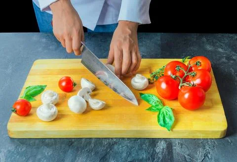 Professional chef cuts vegetables with a sharp knife from Damascus steel. Stock Photos