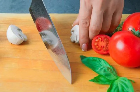 Professional chef cuts vegetables with a sharp knife from Damascus steel. Stock Photos