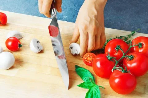 Professional chef cuts vegetables with a sharp knife from Damascus steel. Stock Photos