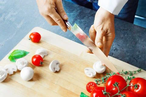 Professional chef cuts vegetables with a sharp knife from Damascus steel. Stock Photos