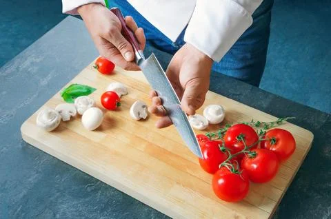 Professional chef cuts vegetables with a sharp knife from Damascus steel. Stock Photos