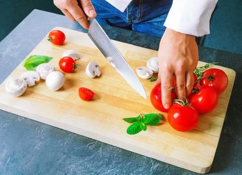 Professional chef cuts vegetables with a sharp knife from Damascus steel. Stock Photos