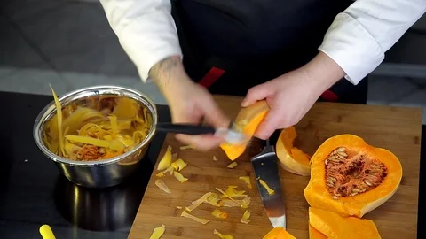 Professional chef is cutting and peeling a pumpkin. Stock Footage 88943373