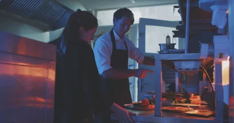 Professional chef explaining dish to waitress in the kitchen Stock Footage 203560527