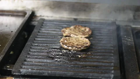 Professional chef flipping grilled beef burger patty with metal spatula over fla Video stock 307058570