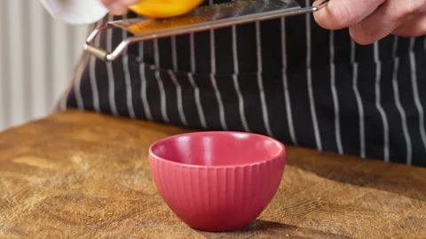 Professional chef grates orange peel with a metal grater. Slow motion 50 fps. Stock Footage 301075117