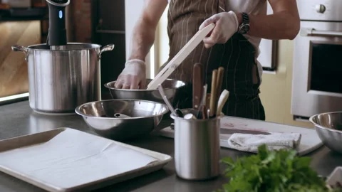 Professional chef grating beets with a mandolin into a bowl in interior kitchen Stock Footage 199462242