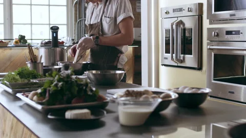 Professional chef grating beets with a mandolin into a bowl while other chefs ar Stock Footage 199463726