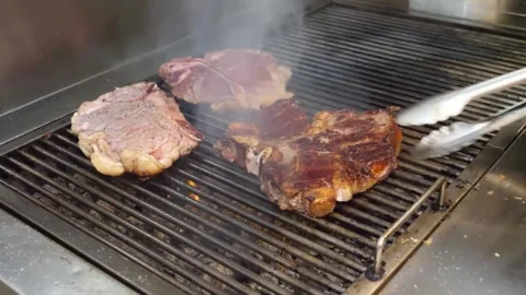 Professional Chef Grilling Thick T-Bone Steaks on Industrial Metal Grate with Sm Vídeos de archivo 332815133
