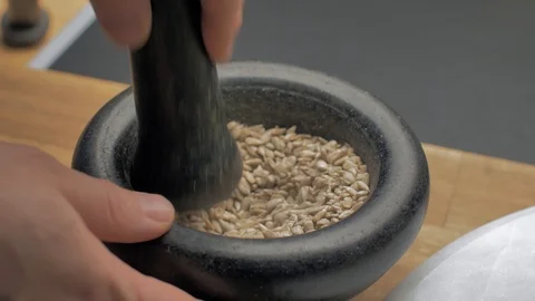 A professional chef hand pounding nuts in mortar Vidéo 97145655