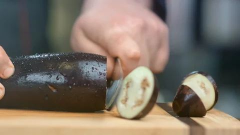 Professional chef hands cuts eggplant on wooden board using knife. Close up shot Stock Footage 124154601