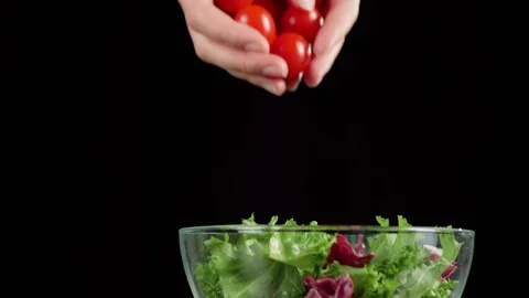 Professional chef hands pour fresh cherry tomatoes in glass bowl with lettuce Stock Footage 129745815