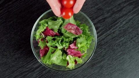 Professional chef hands pour fresh juicy cherry tomatoes in bowl with lettuce Stock Footage 129745880