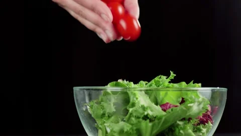 Professional chef hands pour fresh cherry tomatoes in glass bowl with lettuce Stock Footage 130995280