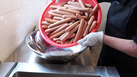 Professional Chef Holding a Red Plastic Basket of Raw Hot Dog Sausages in a Comm Stockbeeldmateriaal 331955625