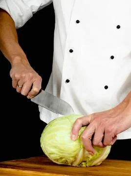 Professional chef holding a sharp cooking knife onto a whole cabbage Profe... Stock Photos