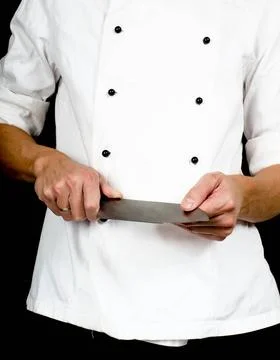 Professional chef holding a sharp cooking knife in hands wearing a chefs j... Stock Photos