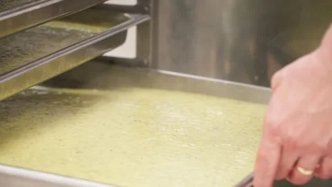Professional chef in an industrial kitchen pouring hot, steaming vegetable Stock Footage 337708183