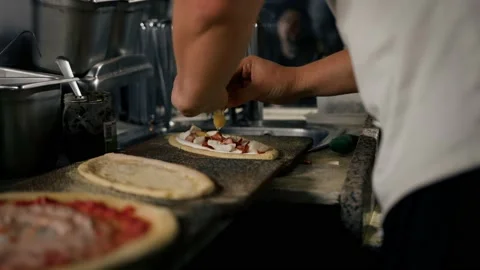 Professional chef makes traditional pizza. Chef adds ingredients to a small p Stock Footage 221271572