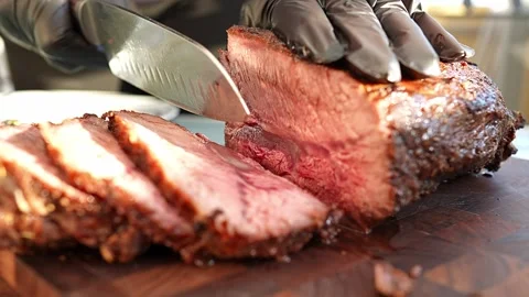 A professional chef masterfully slicing a perfectly cooked, savoury roast dish Stock Footage 284003513
