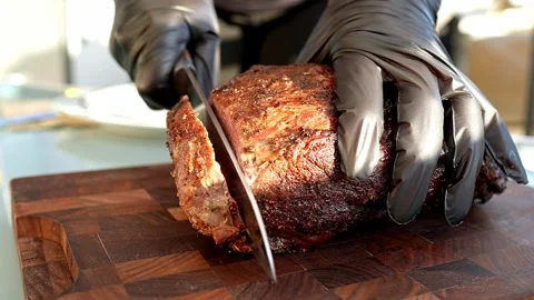 A professional chef masterfully slicing a perfectly cooked, savoury roast dish Vidéo 284003540
