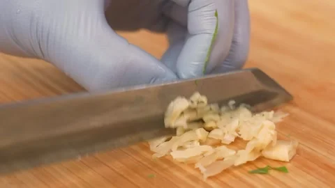 Professional Chef in Nitrile Gloves Finely Chopping Fresh Garlic on Wooden Board Stock Footage 333500737