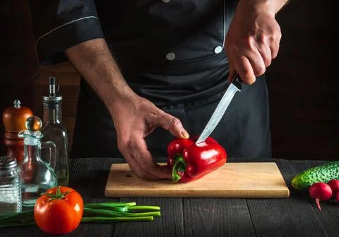 Professional chef or cook cutting red peppers for salad on restaurant kitchen Stock Photos