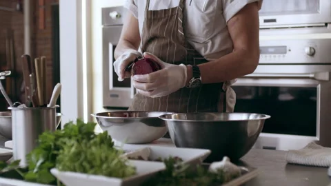 A professional chef peeling beets and putting them in a bowl in interior kitchen Stock Footage 199460911