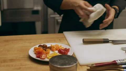 Professional chef placing sliced tomatoes onto a plate in industrial kitchen wit Stock Footage 199456436