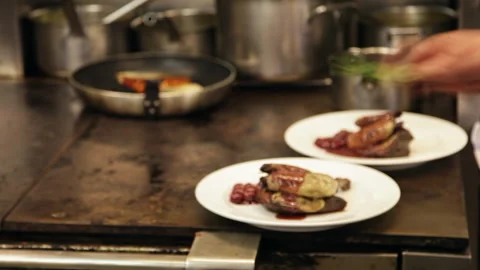 Professional Chef Plating Gourmet Meat Dishes with Microgreens in Kitchen Stockbeeldmateriaal 343724854