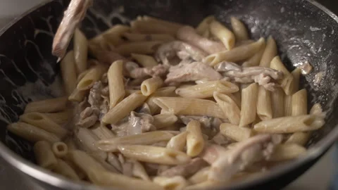 Professional chef plating a hot dish of penne pasta with chicken Stock-Footage 333589242