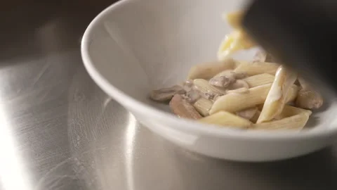 Professional chef plating a hot dish of penne pasta with chicken Stock Footage 333596697