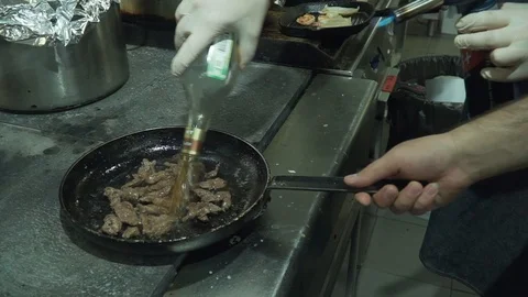 A professional chef prepares the meals. The meat in the pan is burning. Burning Stock Footage 110792686