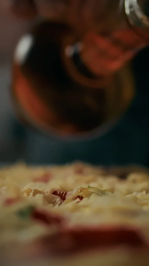 A professional chef prepares pizza by adding olive oil to the pizza toppings Stock Footage 331529437