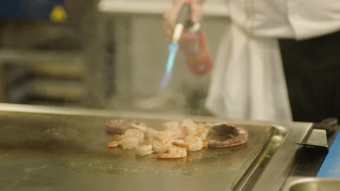 A professional chef prepares shrimp in the restaurant kitchen. Professional Stockbeeldmateriaal 232562828