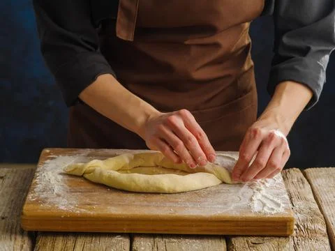 Professional chef preparing a cheese pie on a wooden cutting board, dark blue Foto stock